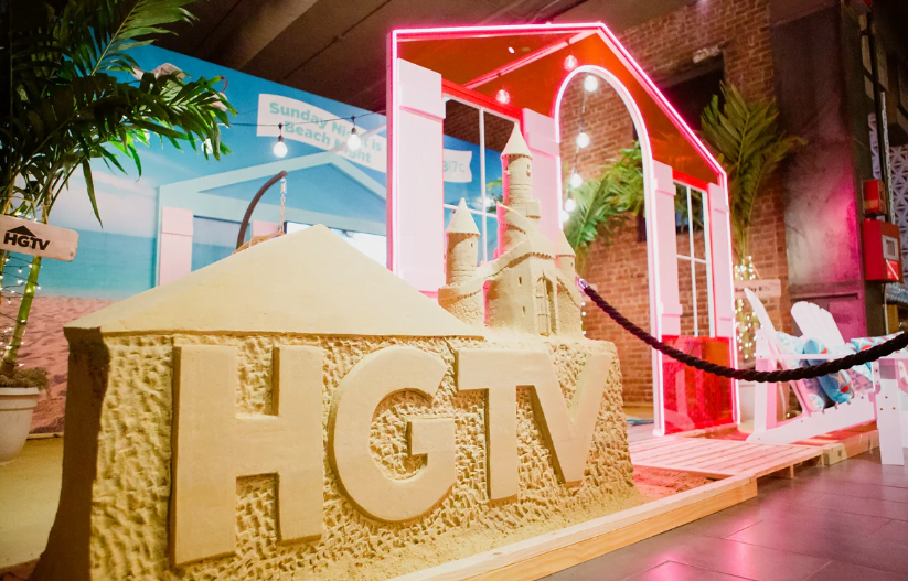 HGTV stage with a beach scene and deck chairs and fake sand
