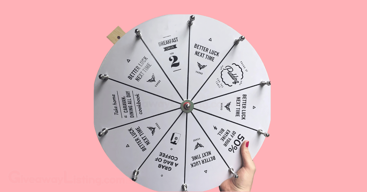 a person's hand holding a raffle wheel in a light pink background.