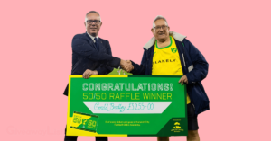 winner of a 50/50 raffle with a staff and the raffle winners cheque.