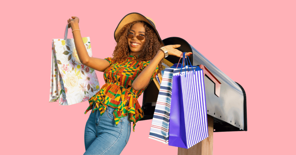 a woman excitedly holding bags of freebies with a mailbox behind her.
