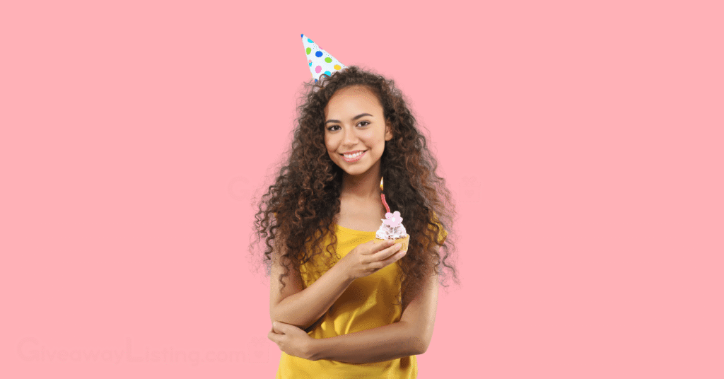 a happy birthday celebrant holding a cupcake with a candle on it.