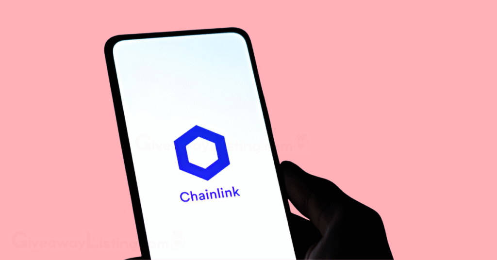 A person's hand holding a phone with the screen showing the Chainlink logo.