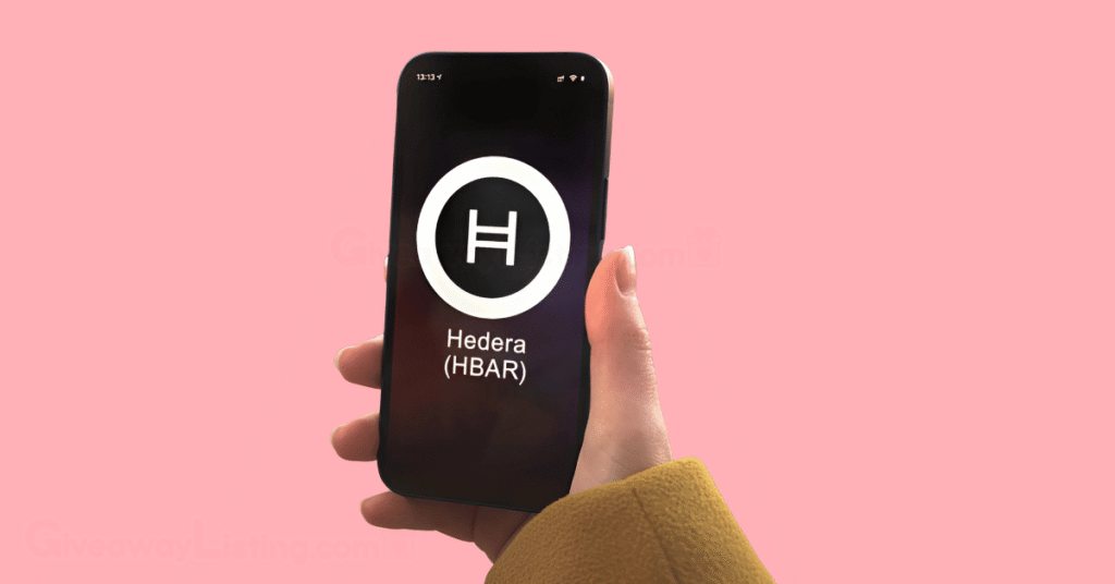 a person's hand holding a phone with the screen showing the Hedera logo.